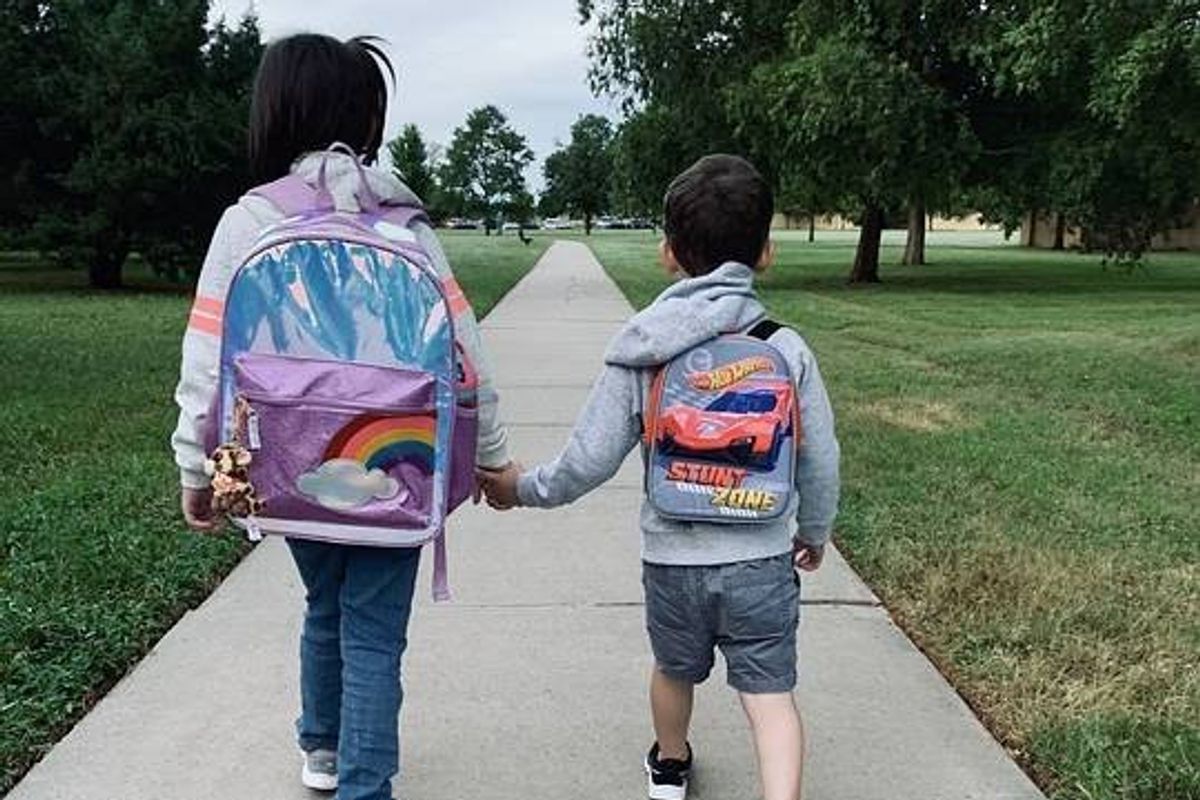 Two children holding hands walking to school